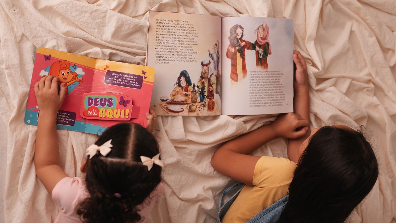 Mãe com bebê no colo folheando um livro cartonado